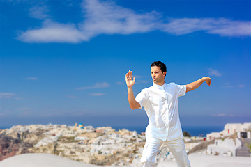 Image showing Handsome man practicing Tai Chi of the rooftops in Oia Santorini