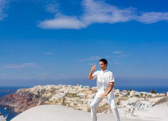 Image showing Handsome man practicing Tai Chi of the rooftops in Oia Santorini