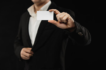 Image showing The businessman in black costume showing credit card or visiting card