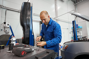 Image showing mechanic man with wrench repairing car at workshop