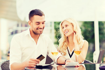 Image showing happy couple with bank card and bill at restaurant