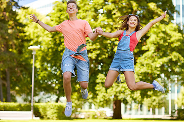 Image showing happy teenage couple jumping at summer park