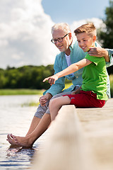 Image showing grandfather and grandson sitting on river berth