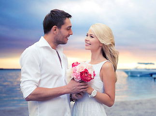 Image showing happy couple with flowers over beach background