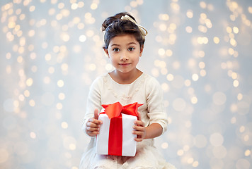 Image showing smiling little girl with gift box over lights