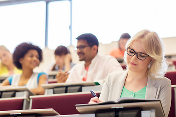 Image showing student girl writing to notebook in lecture hall