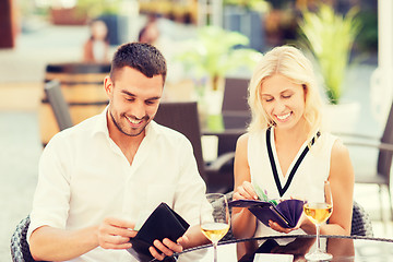 Image showing happy couple with wallet paying bill at restaurant