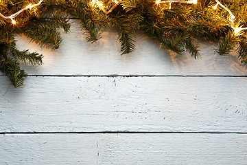 Image showing Christmas wooden background with fir tree and lighted garladnd