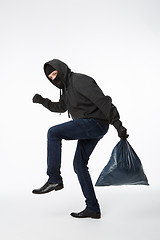 Image showing Thief slinking heavy blue bag