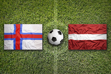 Image showing Faroe Islands vs. Latvia flags on soccer field