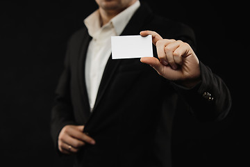 Image showing The businessman in black costume showing credit card or visiting card