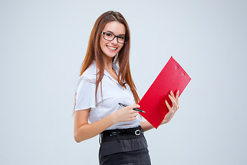 Image showing The smiling young business woman with pen and tablet for notes on gray background