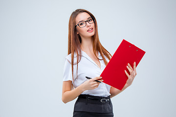 Image showing The smiling young business woman with pen and tablet for notes on gray background