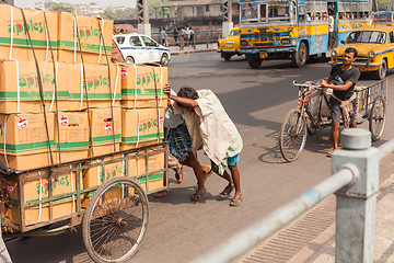 Image showing Men pushing goods