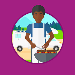 Image showing Man having barbecue in front of camper van.