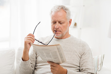 Image showing senior man in glasses reading newspaper at home