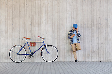 Image showing hipster man in earphones with smartphone and bike