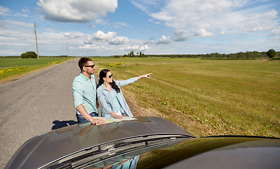 Image showing happy man and woman with road map on car hood