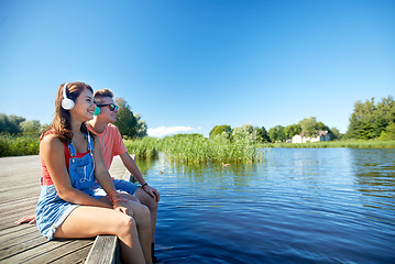 Image showing happy teenage couple with earphones on river berth