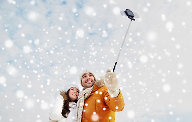 Image showing happy couple taking selfie by smartphone in winter