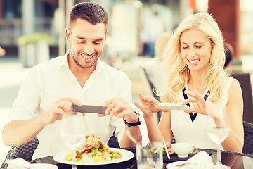 Image showing happy couple with smatphone photographing food