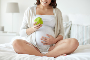 Image showing close up of pregnant woman eating apple at home
