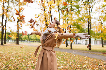 Image showing happy woman having fun with leaves in autumn park