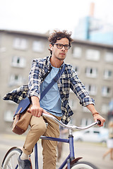 Image showing young hipster man with bag riding fixed gear bike