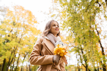 Image showing beautiful woman with maple leaves in autumn park