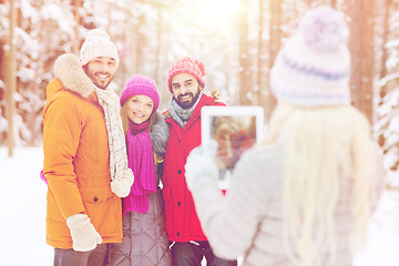 Image showing smiling friends with tablet pc in winter forest