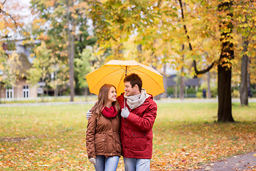 Image showing smiling couple with umbrella in autumn park