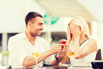 Image showing happy couple with engagement ring and wine at cafe