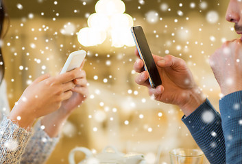 Image showing close up of couple with smartphones at cafe