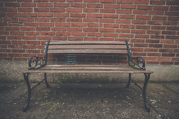 Image showing Antique bench at a red brick wall