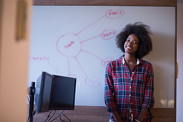 Image showing African American woman writing on a chalkboard in a modern offic