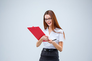 Image showing The smiling young business woman with pen and tablet for notes on gray background