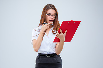 Image showing The young business woman with pen and tablet for notes on gray background