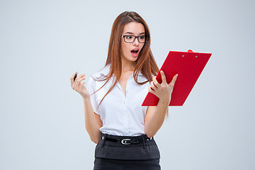 Image showing The young business woman with pen and tablet for notes on gray background