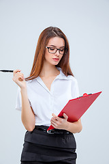 Image showing The young business woman with pen and tablet for notes on gray background