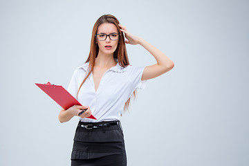 Image showing The young business woman with pen and tablet for notes on gray background