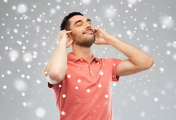 Image showing happy man listening to music over snow background