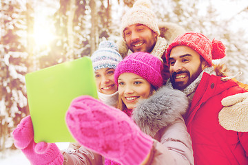 Image showing smiling friends with tablet pc in winter forest