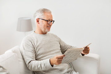 Image showing senior man in glasses reading newspaper at home