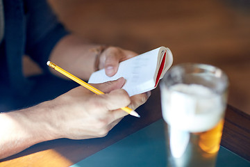 Image showing close up of man with beer and notebook at pub