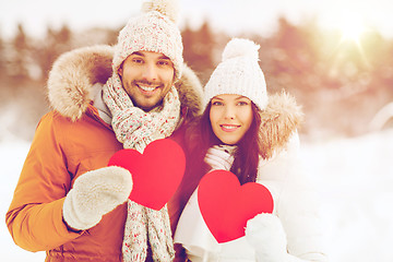 Image showing happy couple with red hearts over winter landscape