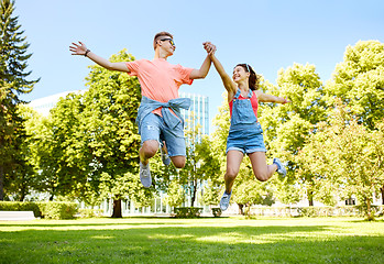 Image showing happy teenage couple jumping at summer park