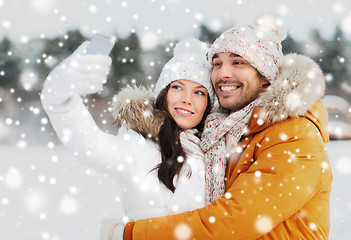 Image showing happy couple taking selfie by smartphone in winter