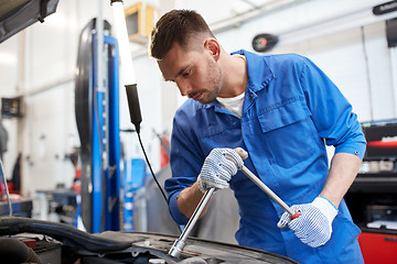 Image showing mechanic man with wrench repairing car at workshop