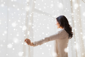 Image showing close up of pregnant woman opening window curtains