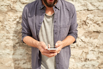 Image showing close up of man with smartphone at stone wall